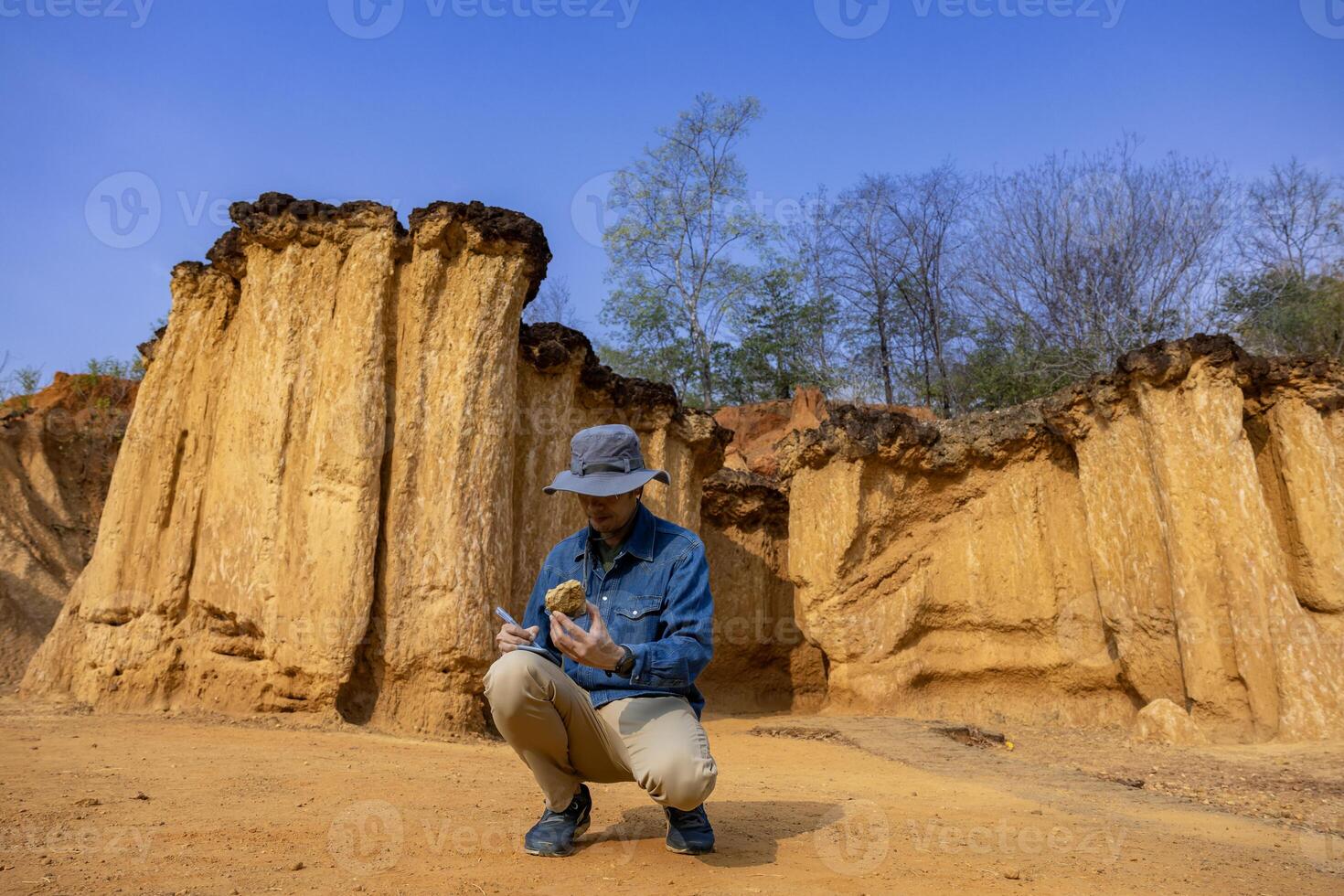 Asian geologist is surveying and exploring the sample rock on the natural sandstone canyon quarry resource site for scientific research and archeology for understanding mother earth photo