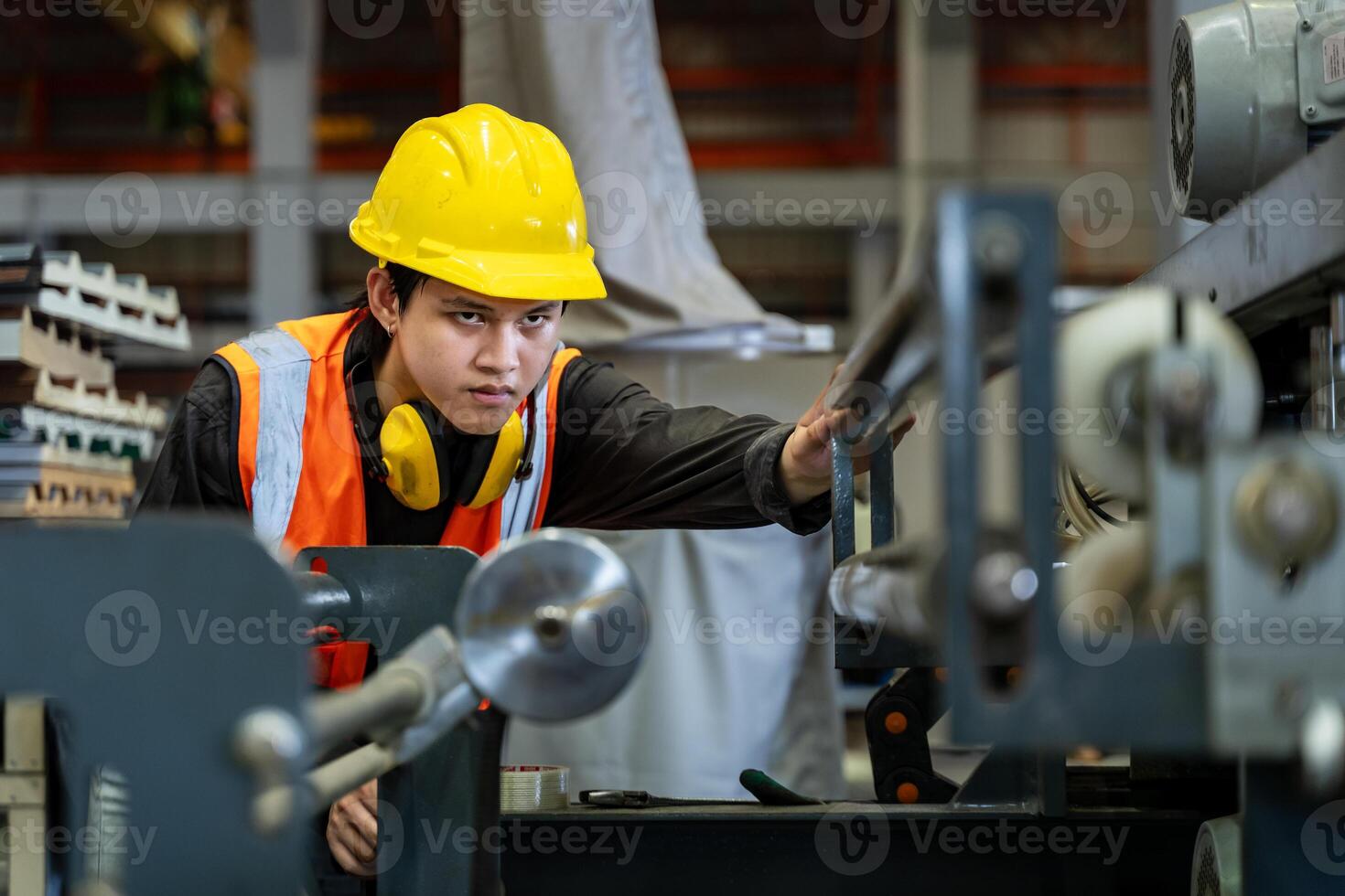 Asian industrial worker is checking setup value of metal sheet roll forming machine inside roof factory for safety industry construction usage photo