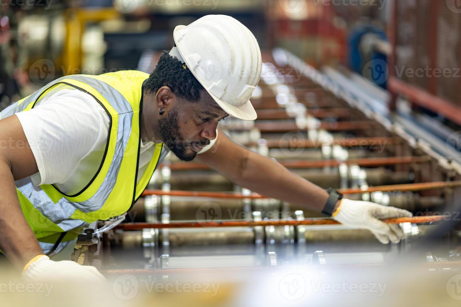 African American industrial worker is checking and adjusting the setup value of metal sheet roll forming machine inside roof factory for safety industry construction photo