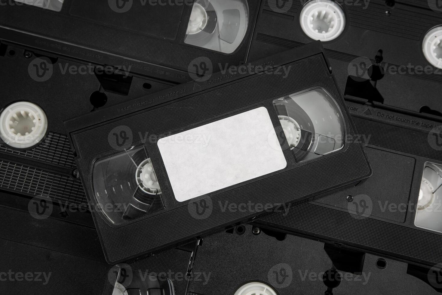 Stacked VHS tapes with a blank white label, black cassette. photo