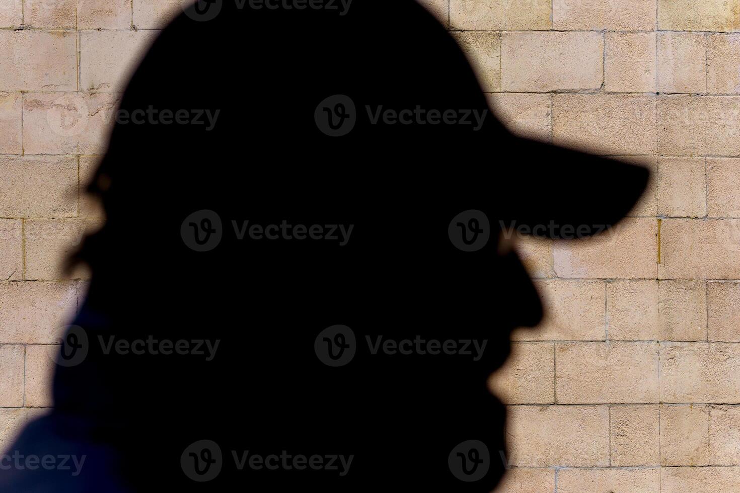 Shadow of a profile of a man's head in a baseball cap against a wall. Human face. photo