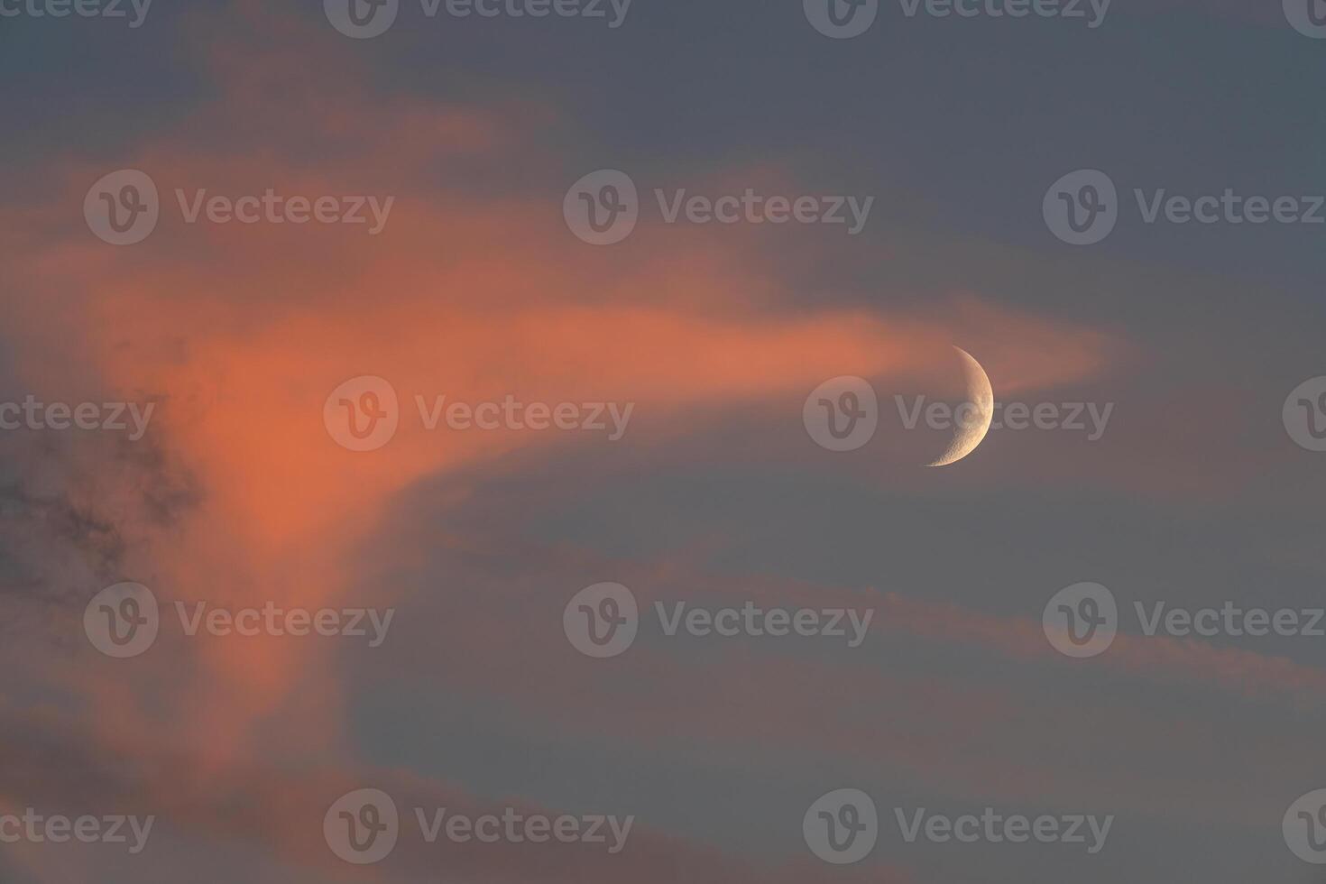 A crescent moon is seen in the sky with a cloud photo