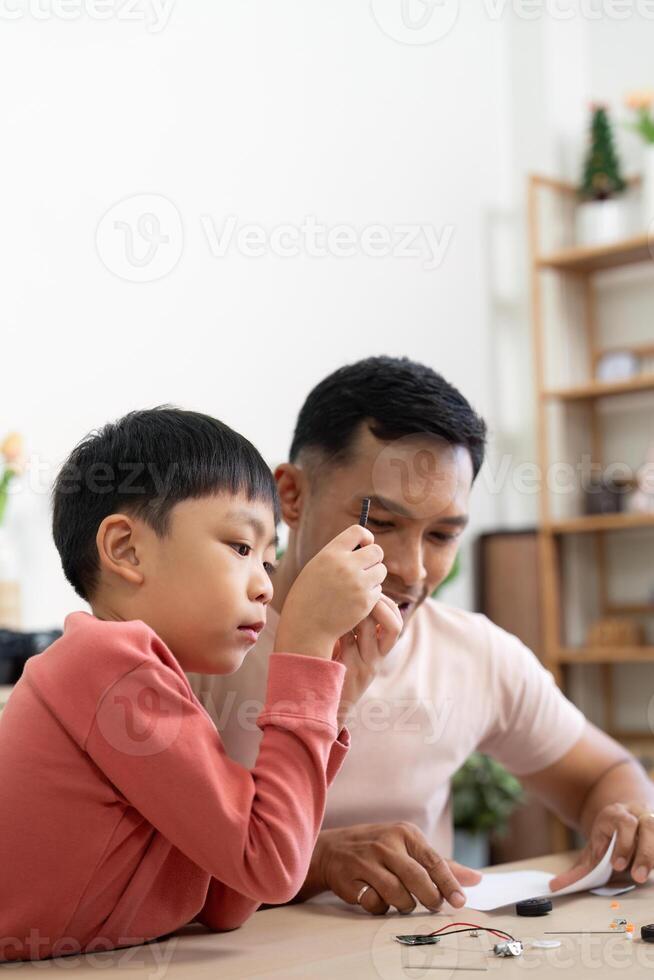 Activity of father and child assembling science kits at home photo