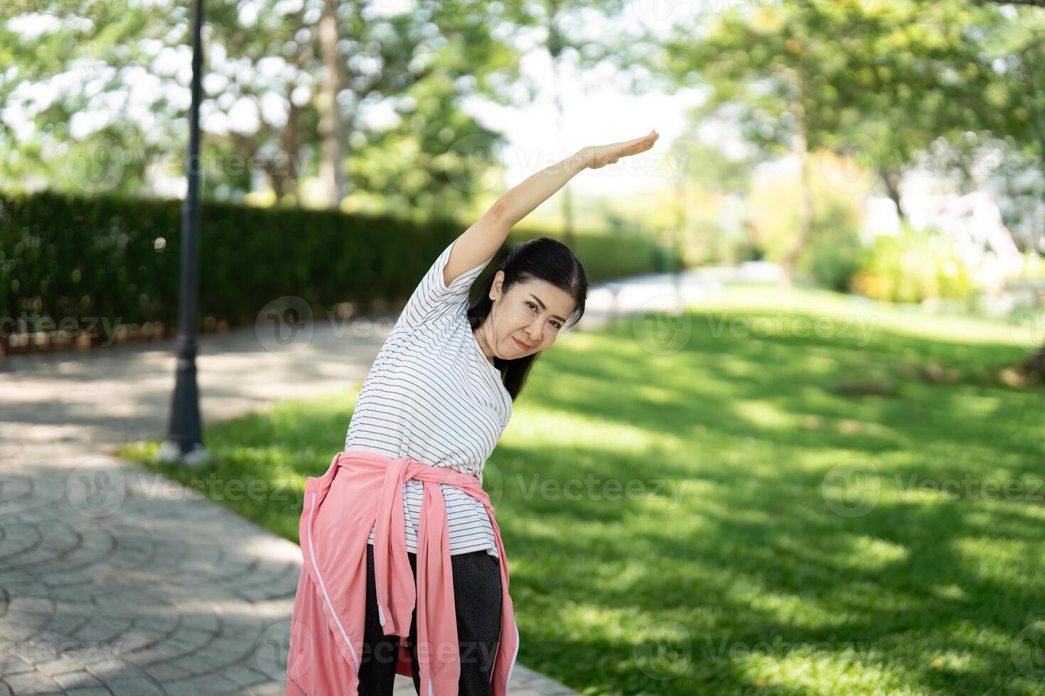 Wellness and fitness. Elderly woman stretching outdoors photo