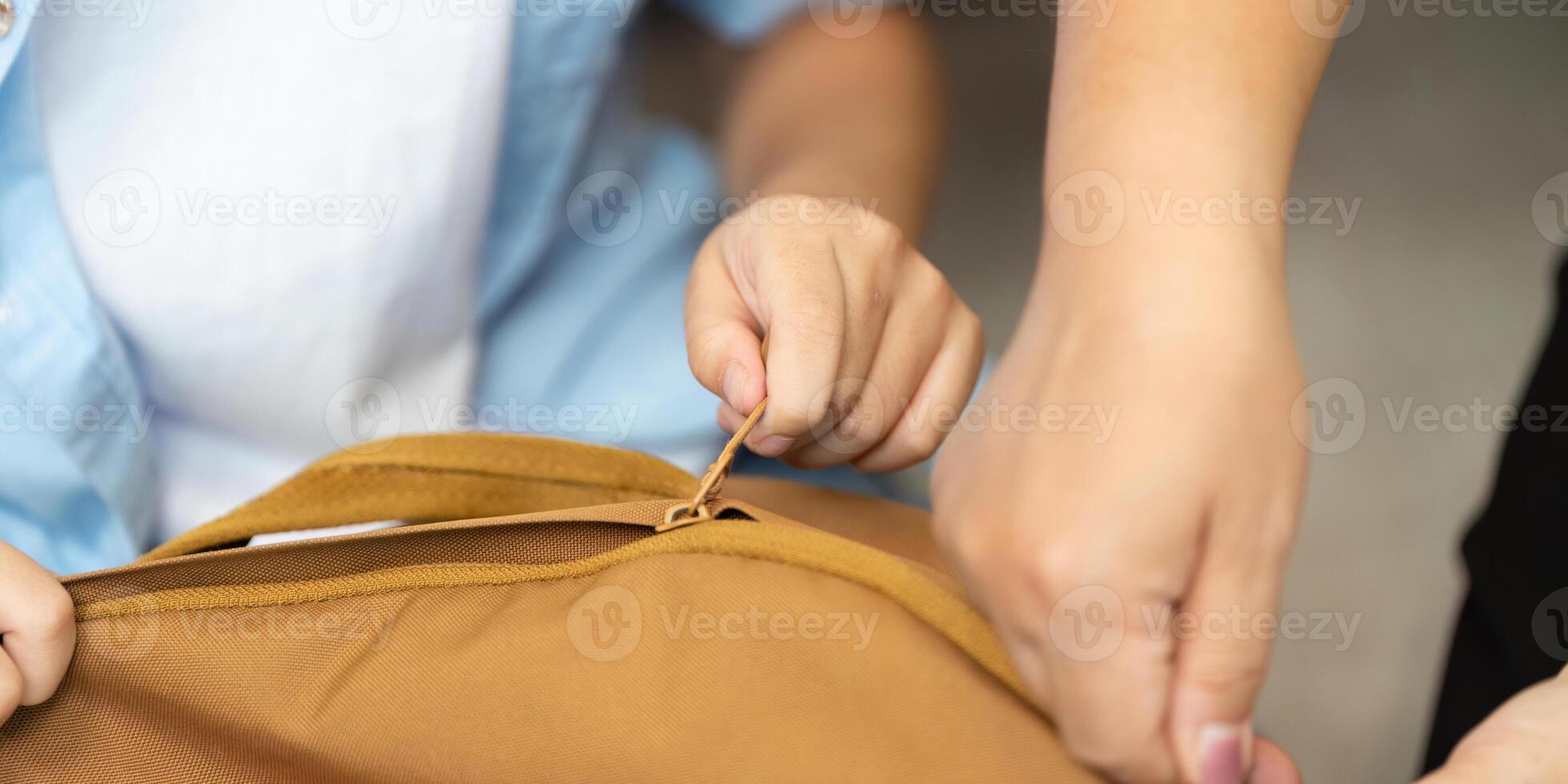 Back to School. Child zipping up backpack with parent assistance. photo