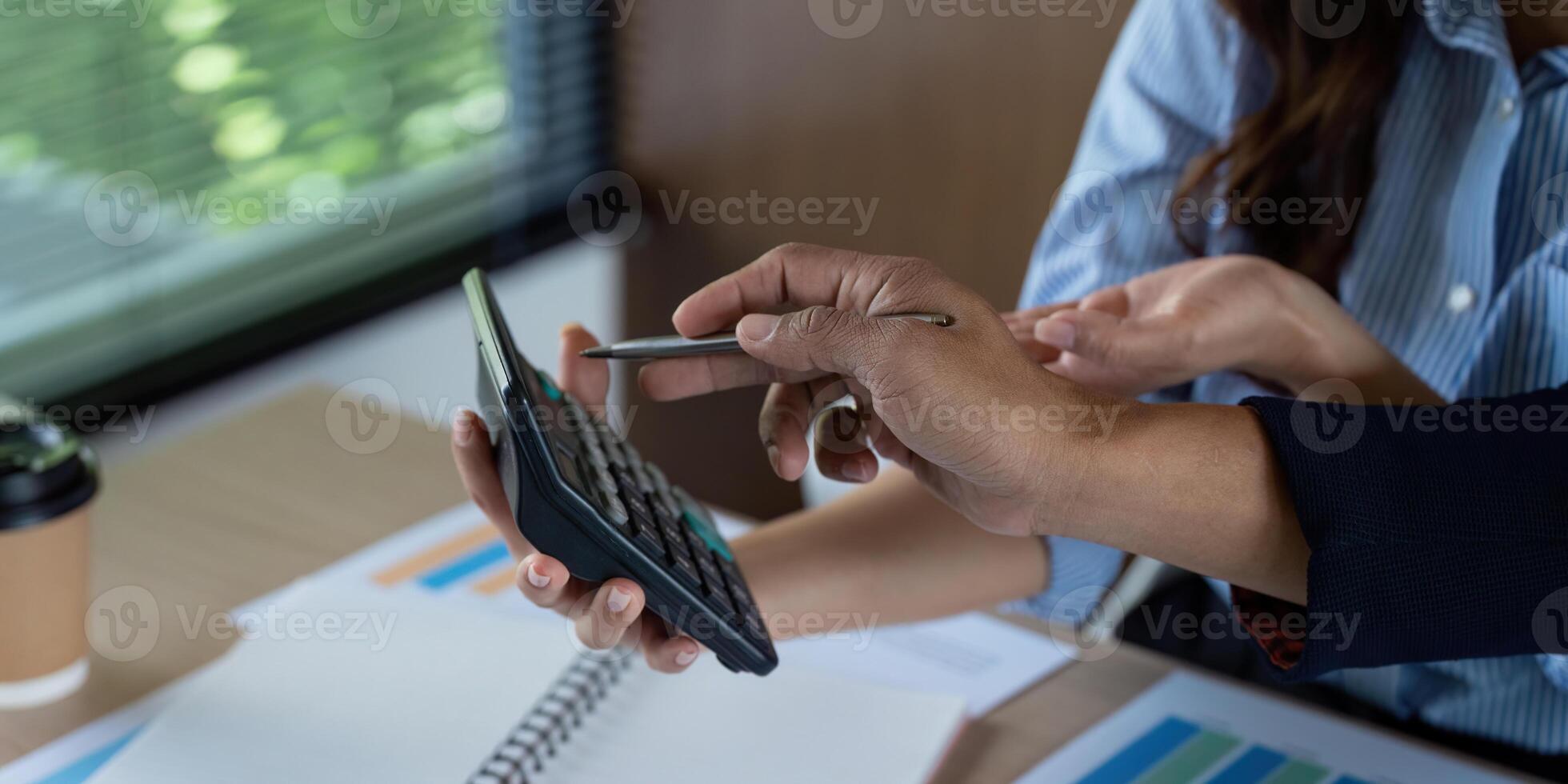 Financial Collaboration. Team members discussing calculations on a calculator during a business meeting. photo