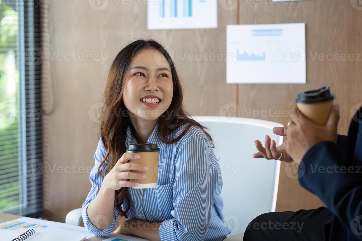 Positive Workplace Interaction. Smiling woman enjoying coffee while engaging in conversation with a colleague. photo