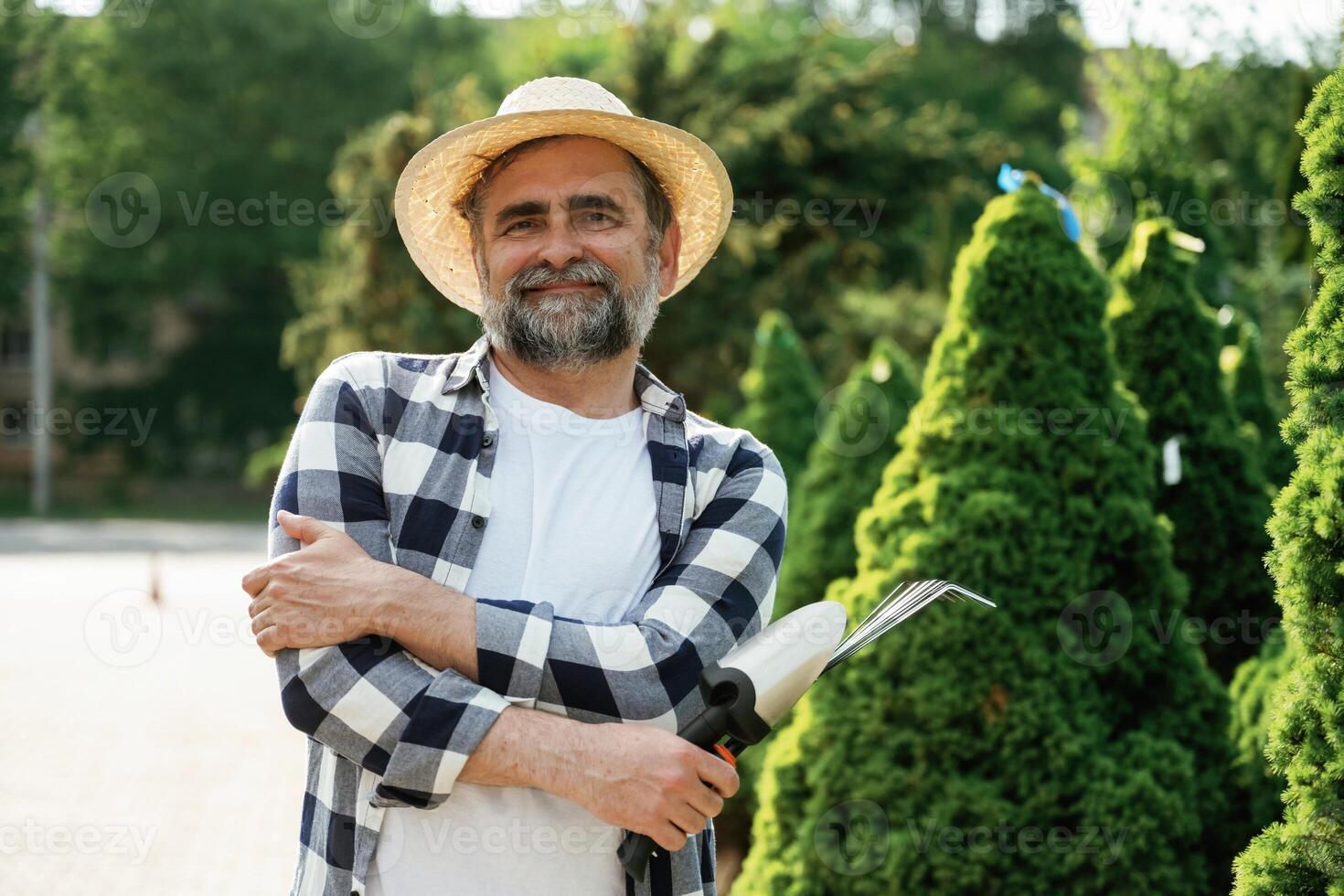 Standing with tools., Senior gardener is at work at daytime photo