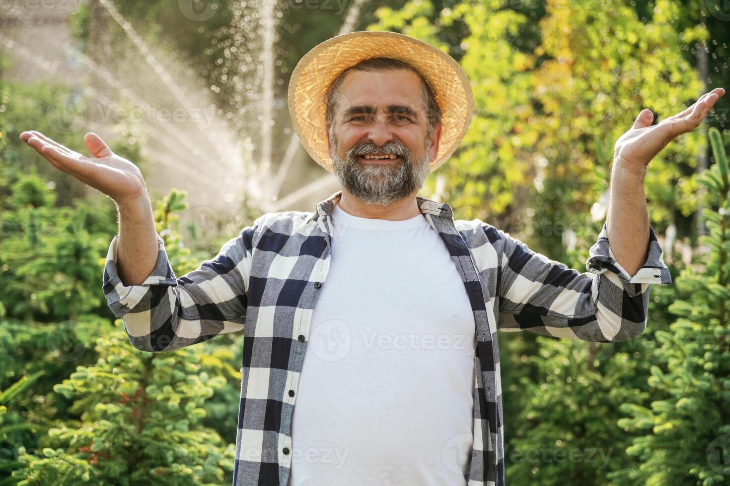 Against automatic watering machine. Senior gardener is at work at daytime photo