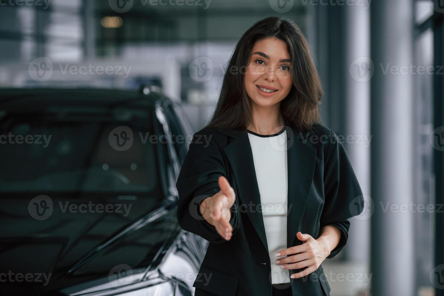Giving a hand to shake,,,, making a deal. Saleswoman in car showroom, selling automobile photo