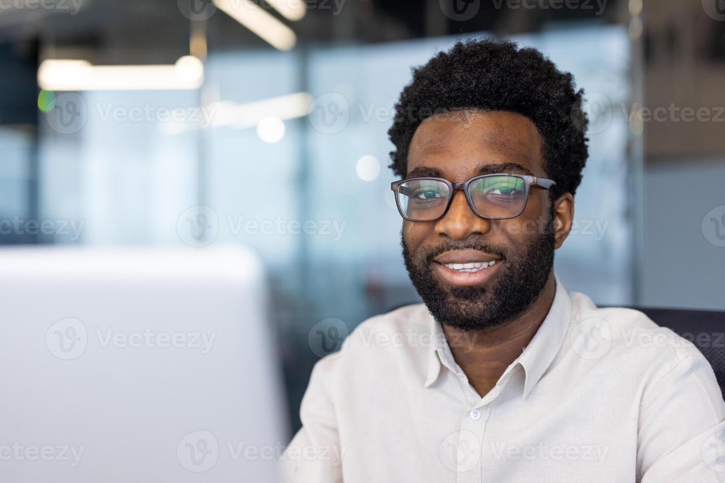 A close-up shot of a smiling professional at work, showing his friendly and confident demeanor in an office environment. photo