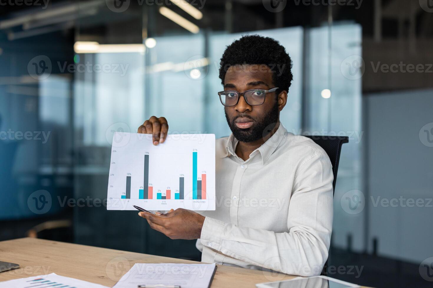 A professional man presents financial data with a graph during a meeting in the office. The analysis is shown with data bars on paper. photo