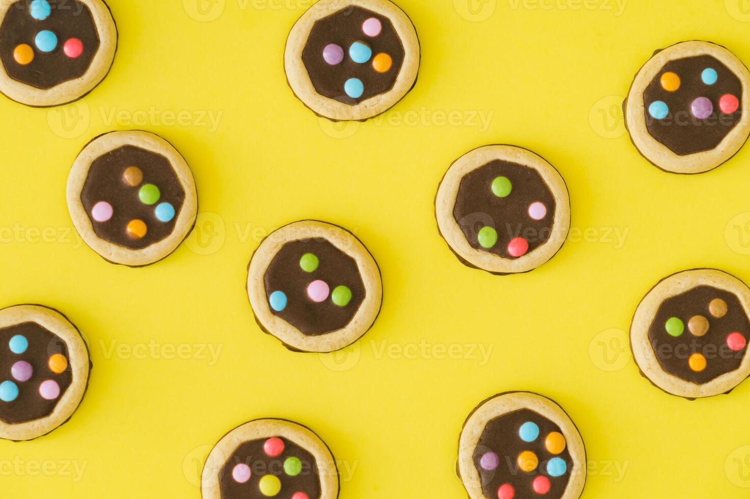 Vibrant pattern composition made of colorful cookies on a bright yellow background. Minimal sweet food concept. Fun, festive, playful and yummy layout. Biscuits aesthetic. Flat lay style. Top view. photo