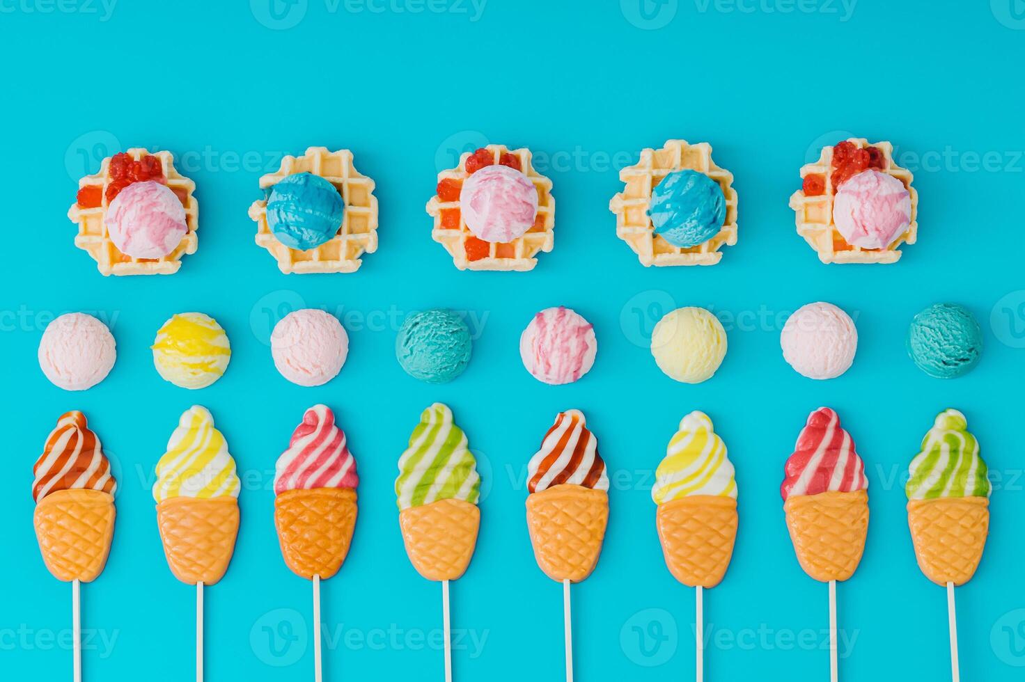 Colorful summer dessert composition with waffles, scoop of ice cream and ice cream shaped lollipops on a light blue background. Bright and vibrant colors. Flat lay style. Top view. photo