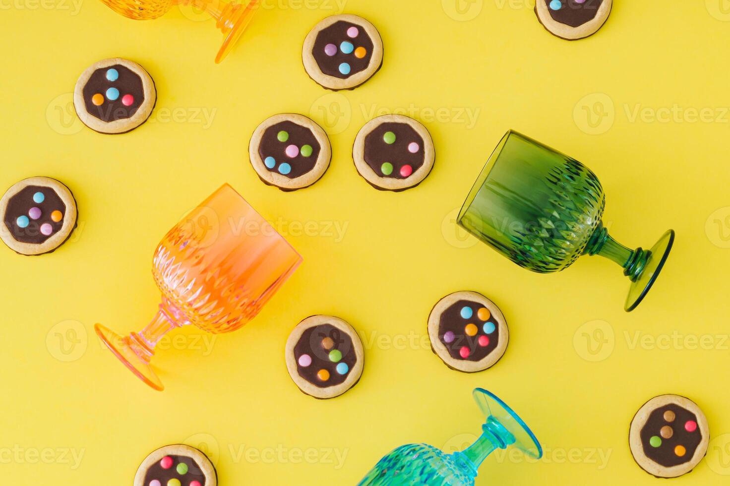 Pattern with colorful cookies and vibrant cocktail glasses on a bright yellow background. Food and drink concept. Trendy party idea. Fun, festive and playful layout. Flat lay style. Top view. photo