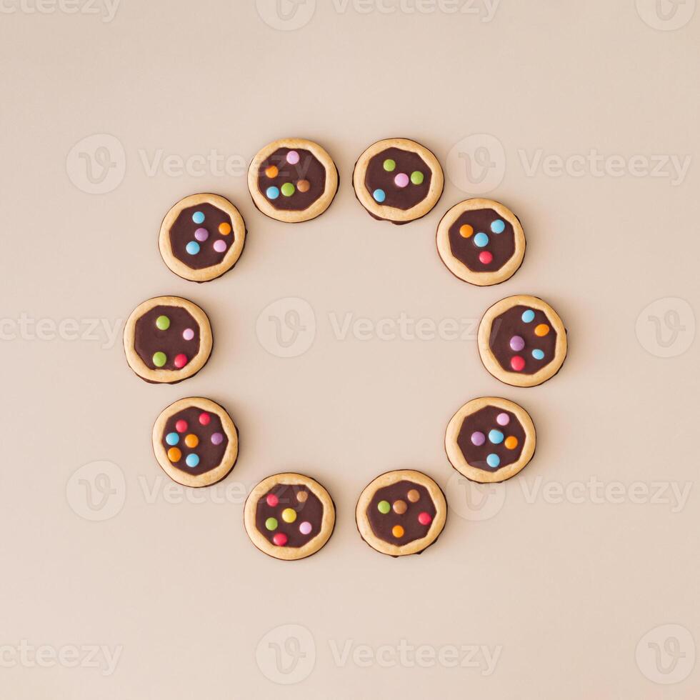 Colorful chocolate cookies on beige background. Minimal sweet food concept. Trendy yummy biscuits idea. Flat lay style. Top view banner. Creative copy space. photo