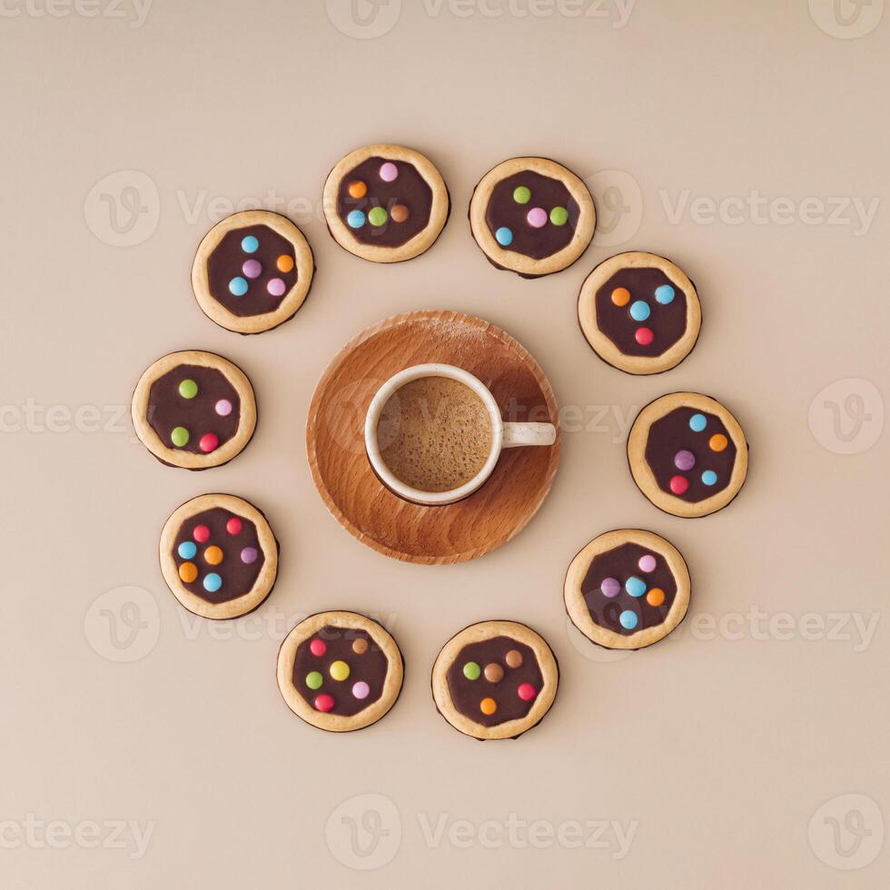 Colorful chocolate cookies with cup of coffee on pastel cream background. Minimal coffee with biscuits concept. Yummy sweet food and hot drink idea. Flat lay style. Top view. photo