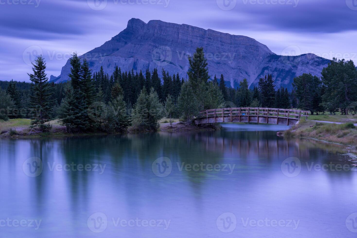 A bridge over a lake and mountains in the background photo