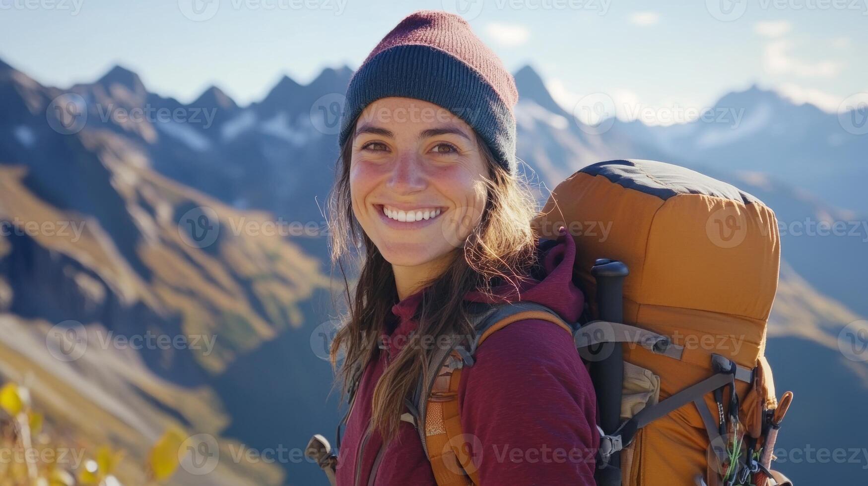 Woman in hiking gear smiles amidst stunning mountains on a sunny day, embracing adventure in nature's beauty photo