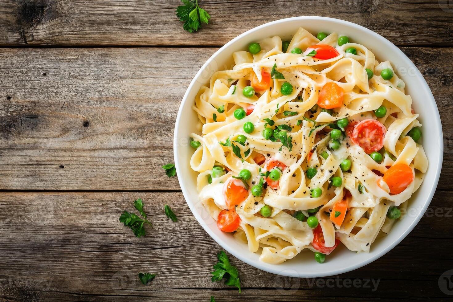 Delicious elbow pasta salad with carrots, onions, tomatoes, and peas in mayonnaise dressing served in a white bowl on wooden table photo