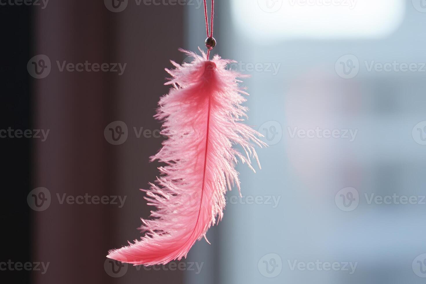 A playful pink feather cat toy teaser hanging from a string, perfect for engaging feline fun indoors photo