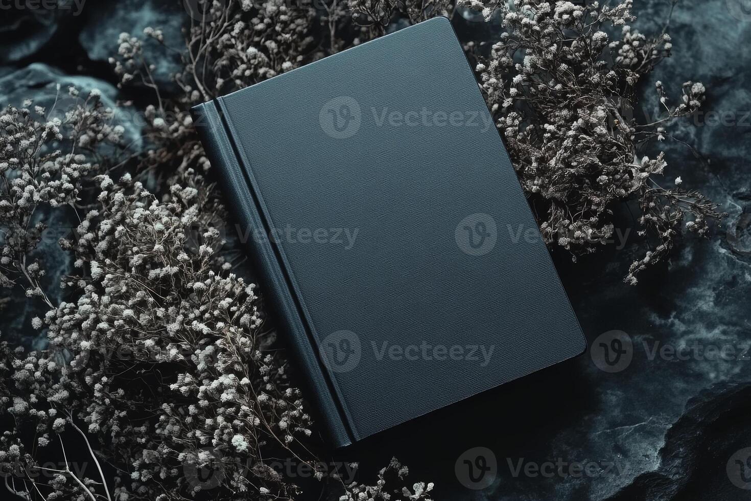 Stylish black book mockup with dark aesthetic placed among dried flowers on textured surface for design presentation photo