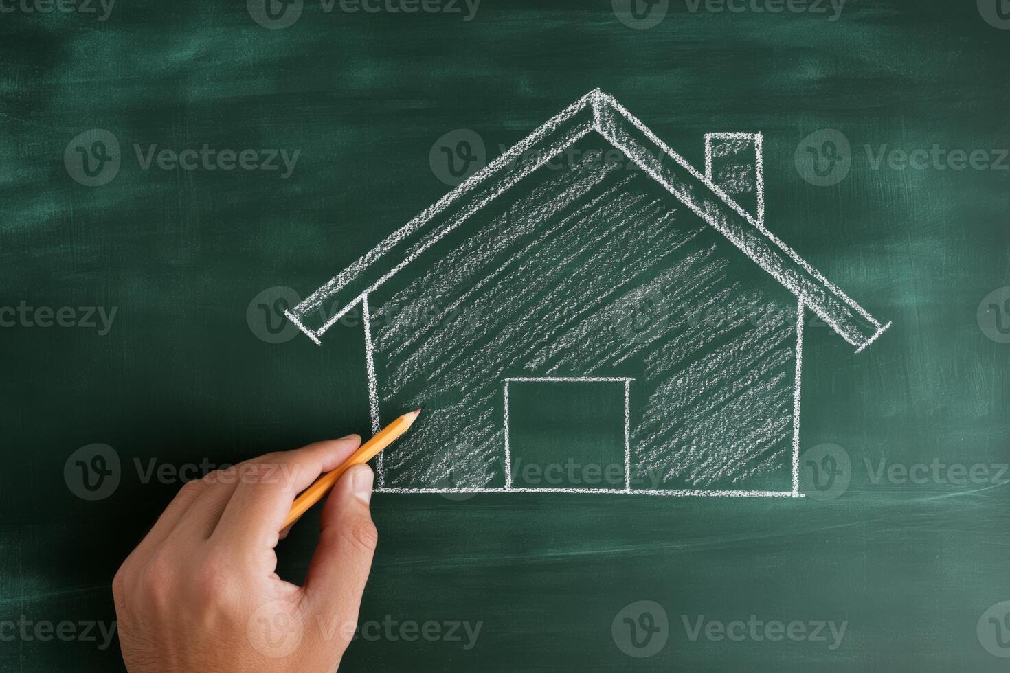 A man drawing a house on a chalkboard representing the concept of home ownership and family stability photo