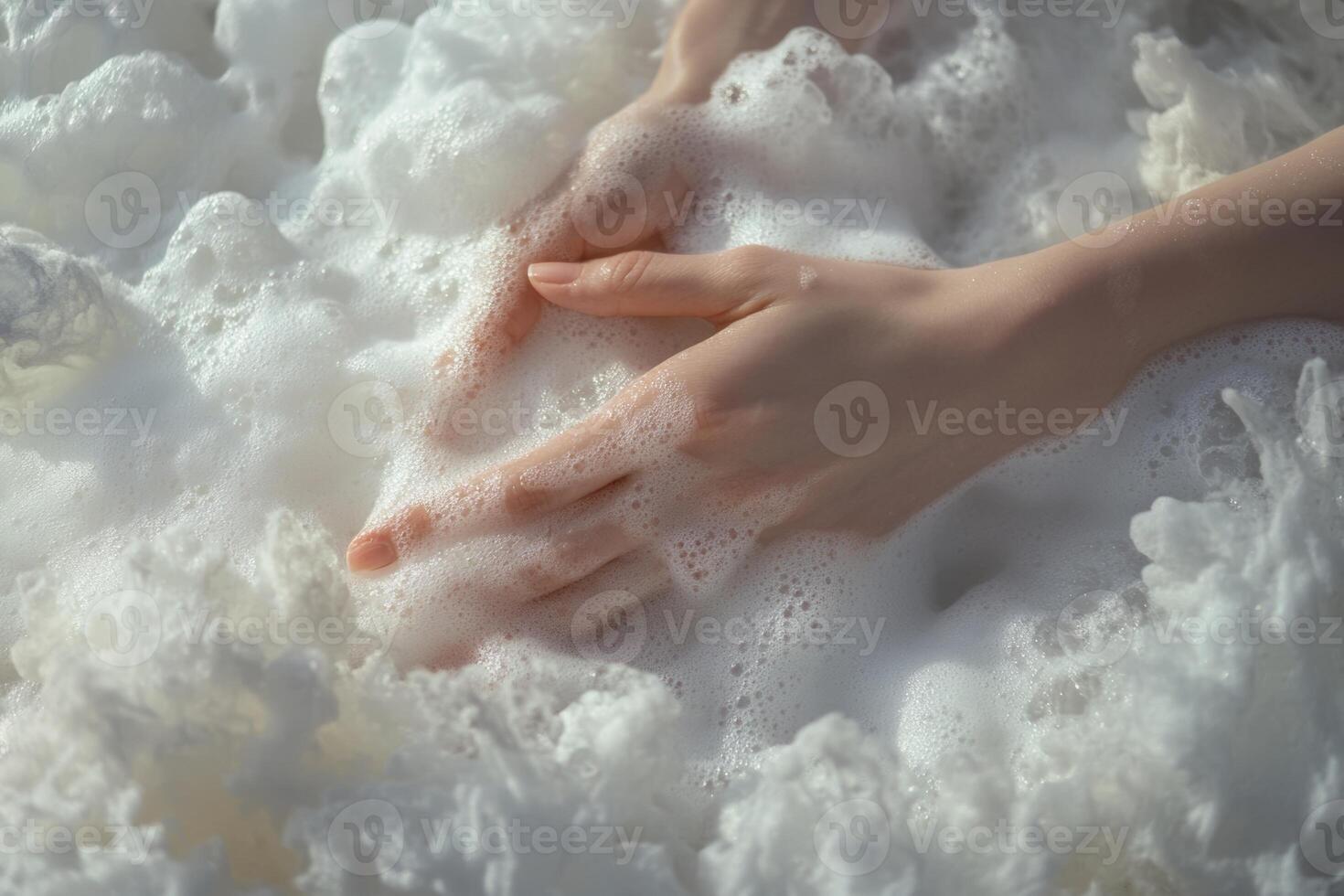 Womens hands gently submerging into fluffy white foam with soft ambient light creating a serene and tranquil atmosphere photo