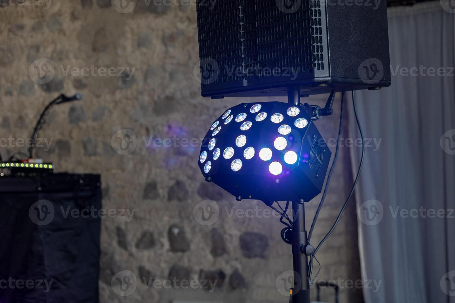 Colorful stage lighting set up for a music event in a rustic venue with stone walls photo