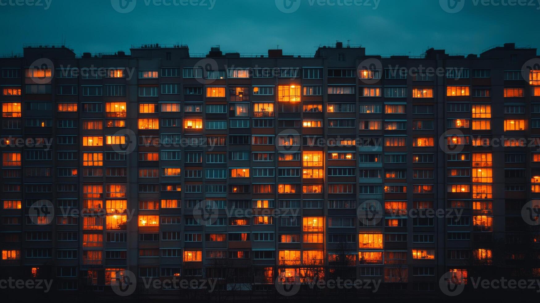 Illuminated windows of a residential building at dusk casting a warm glow in an urban neighborhood photo