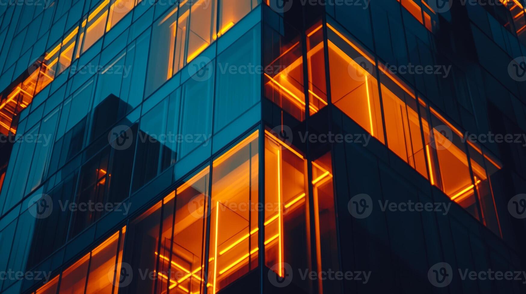 Modern glass building illuminated at night with warm orange lighting creating a striking visual effect in an urban setting photo