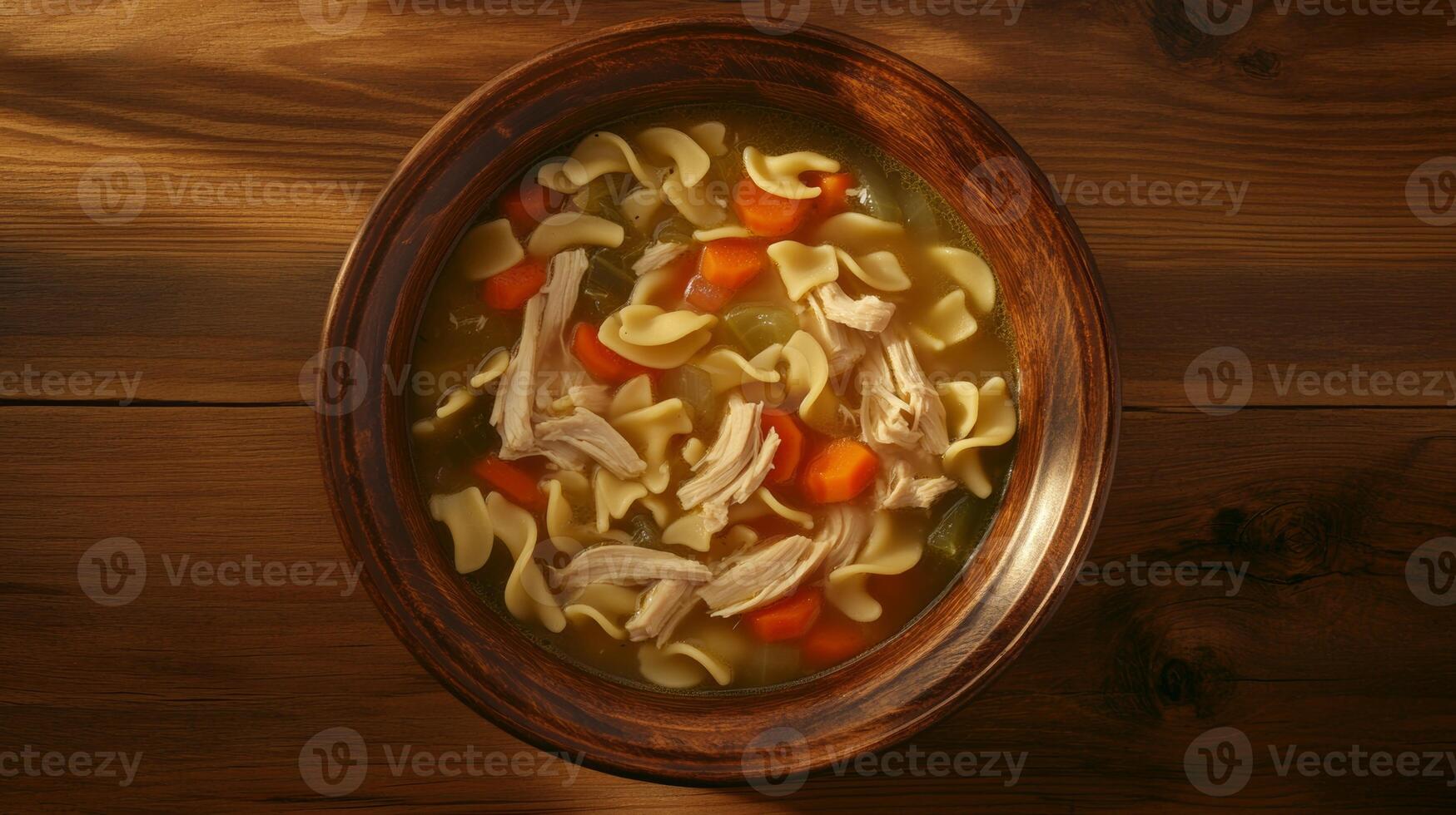 Warm bowl of chicken noodle soup with vegetables served on a wooden table in cozy evening lighting photo
