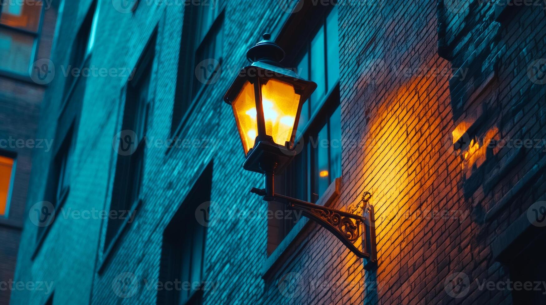 Vintage street lamp illuminates the warm glow on an old brick building in the city at dusk photo