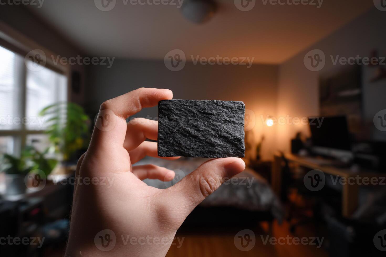 Dark stone rectangular slab held in hand, blurred interior photo