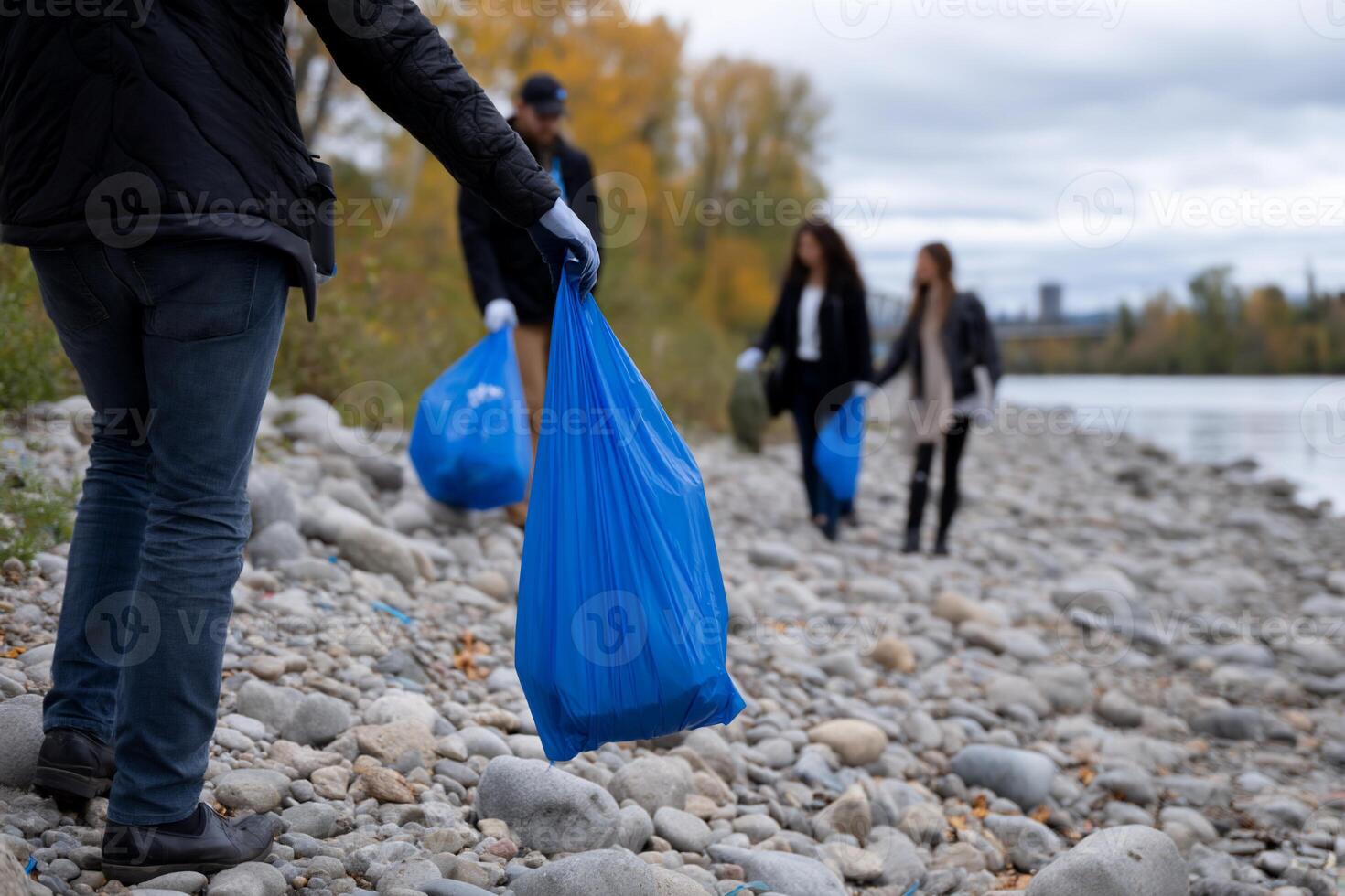 People picking up trash on a rocky riverside photo