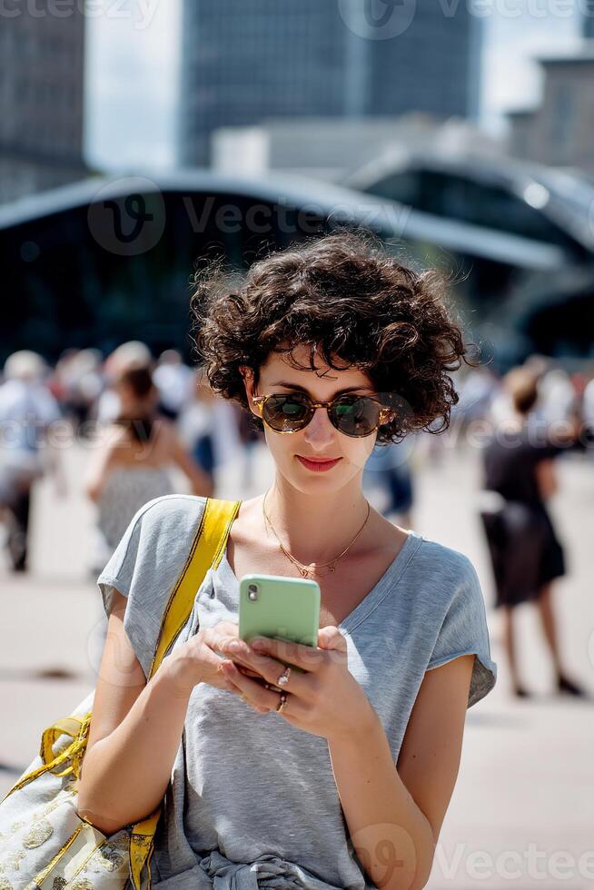 A woman in sunglasses is looking at her phone photo