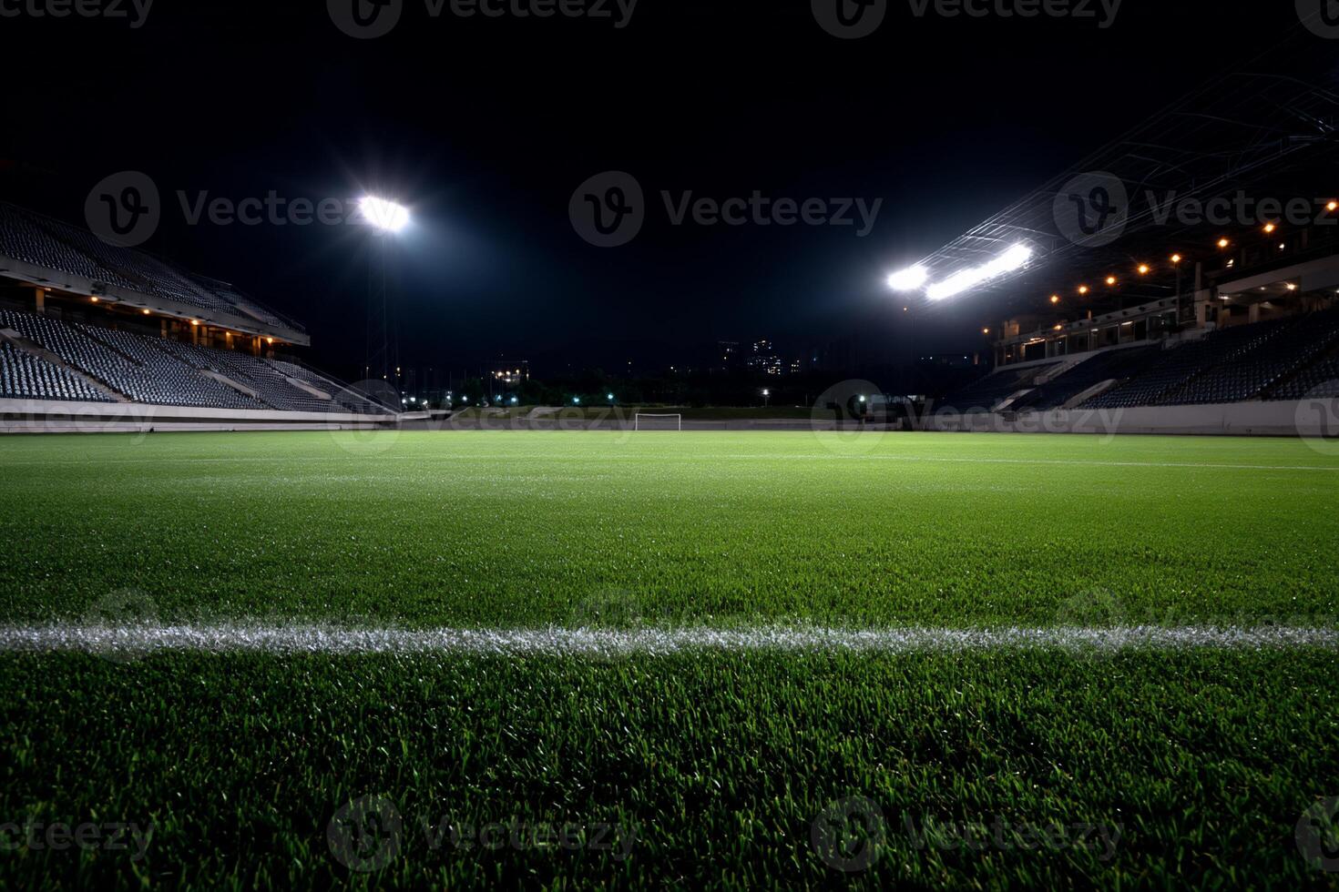 Empty soccer stadium at night, floodlights illuminate green field photo