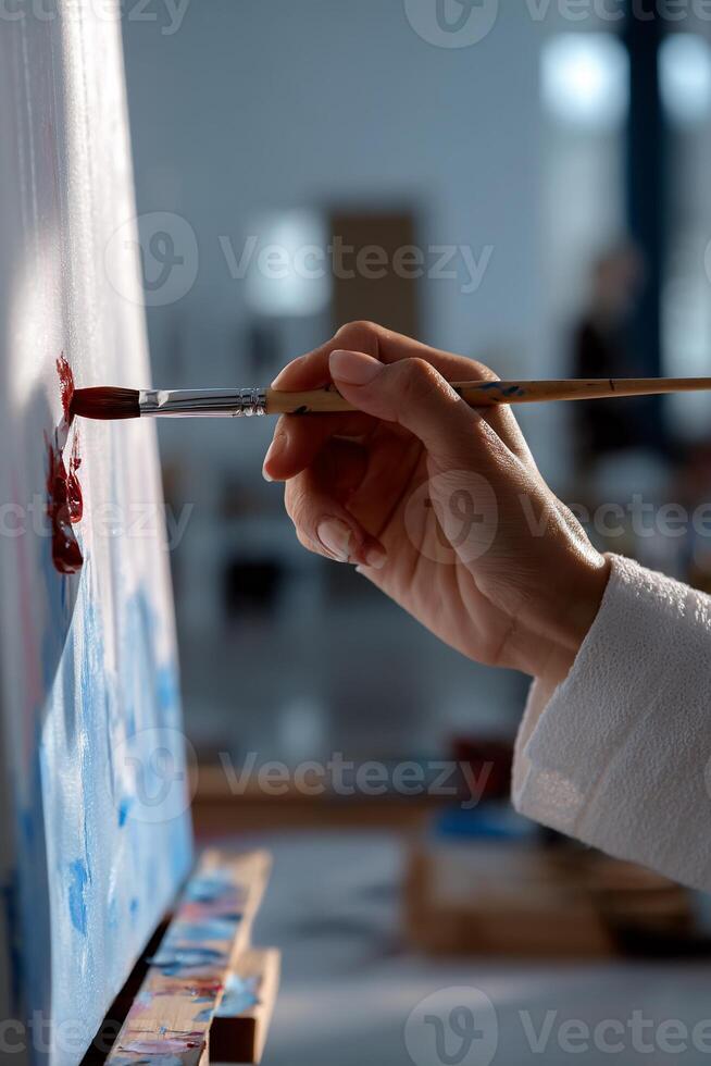 A person is holding a paintbrush and painting on a canvas photo
