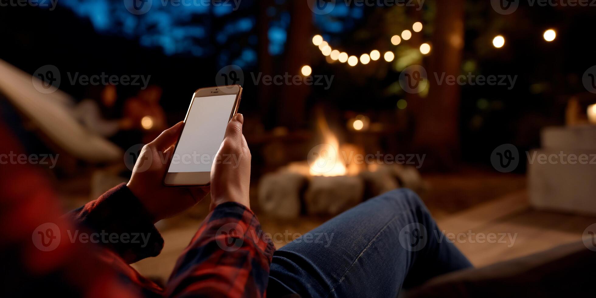Person using phone by campfire outdoors at night photo