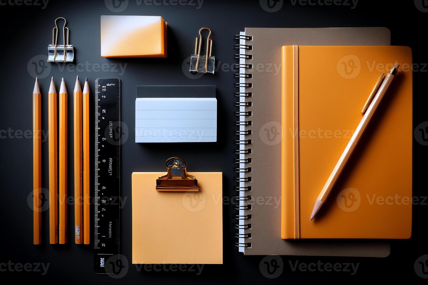 Assorted stationery items, orange and muted gray, on a dark surface photo