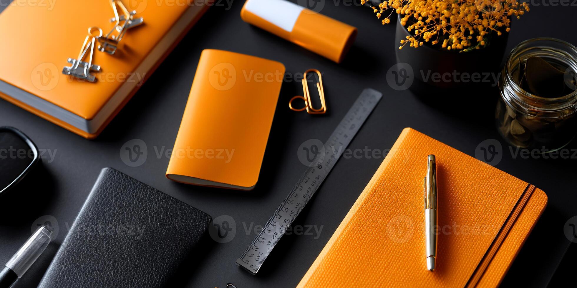Flat lay of orange and black stationery items on a dark surface photo