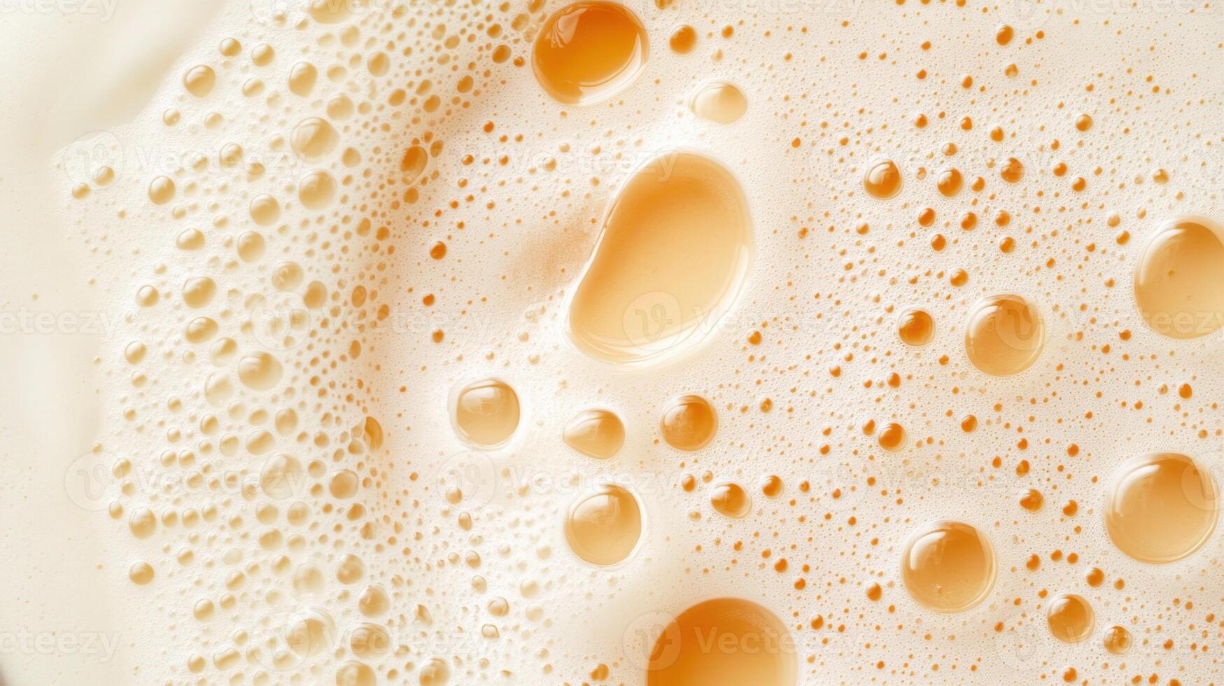 Close up of amber liquid with frothy bubbles and surface tension in varying sizes against a light background. Macro image of textured liquid photo