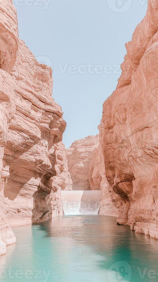 Desert canyon landscape with turquoise water flowing over a dam between tall textured sandstone cliffs under a clear blue sky during daytime photo