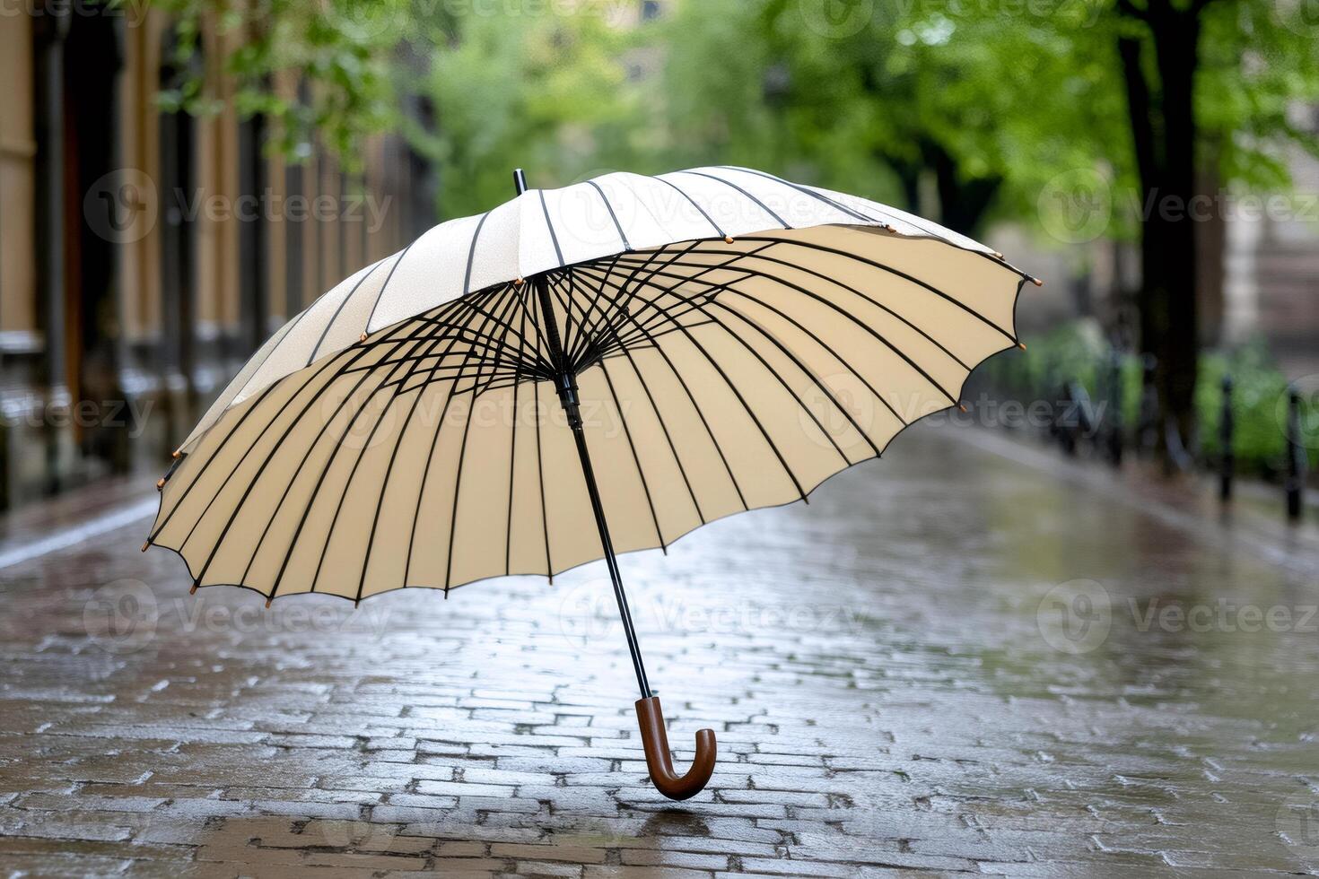 Stylish umbrella standing on wet cobblestone street during rain photo