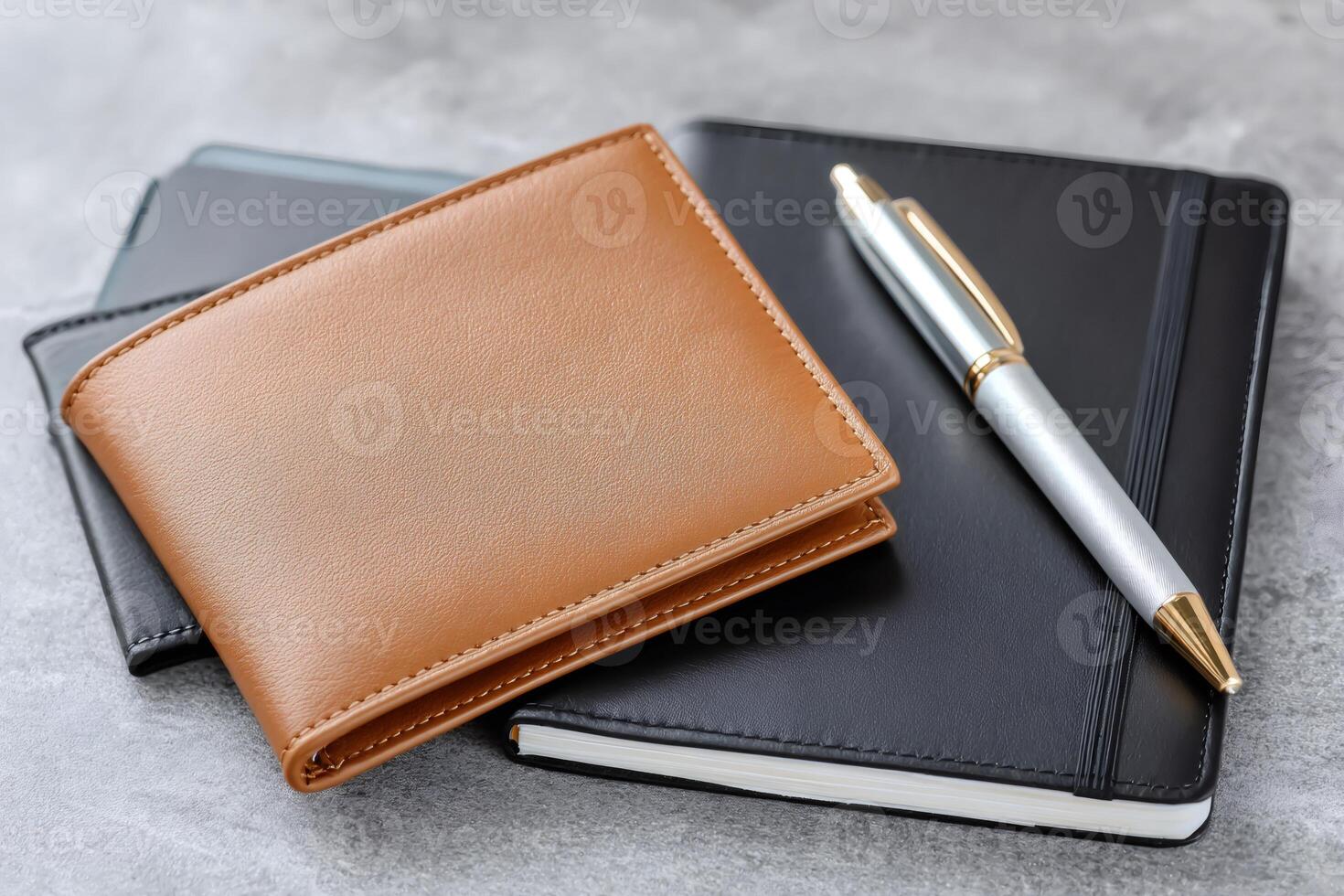Leather wallet, notebook and pen resting on a gray desk photo