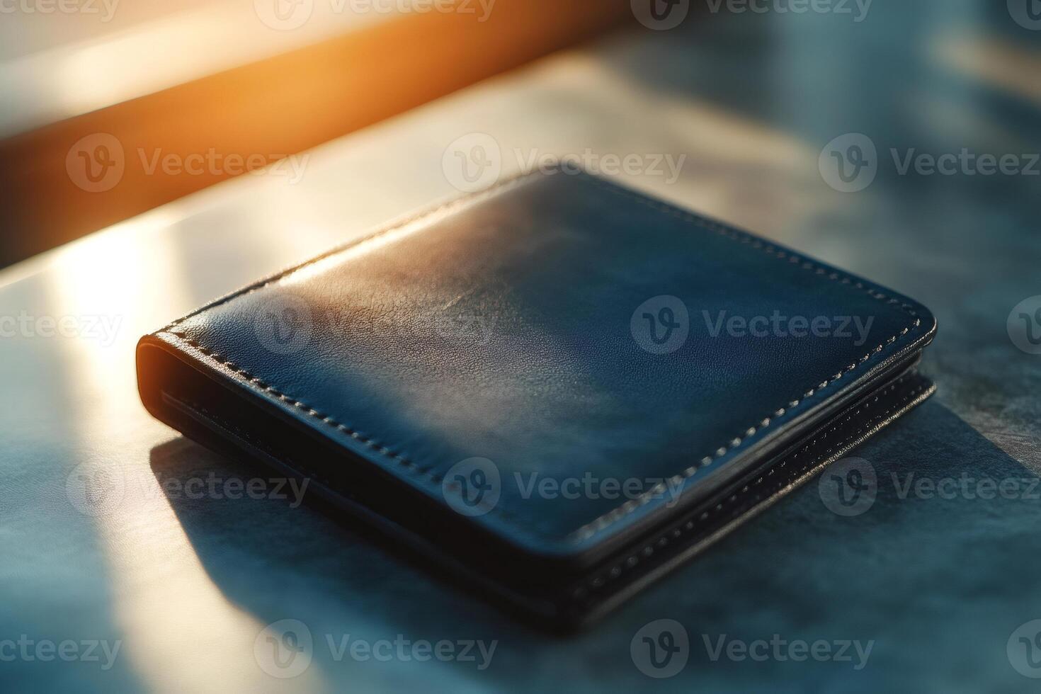 Black leather wallet lying on gray table in warm sunlight photo