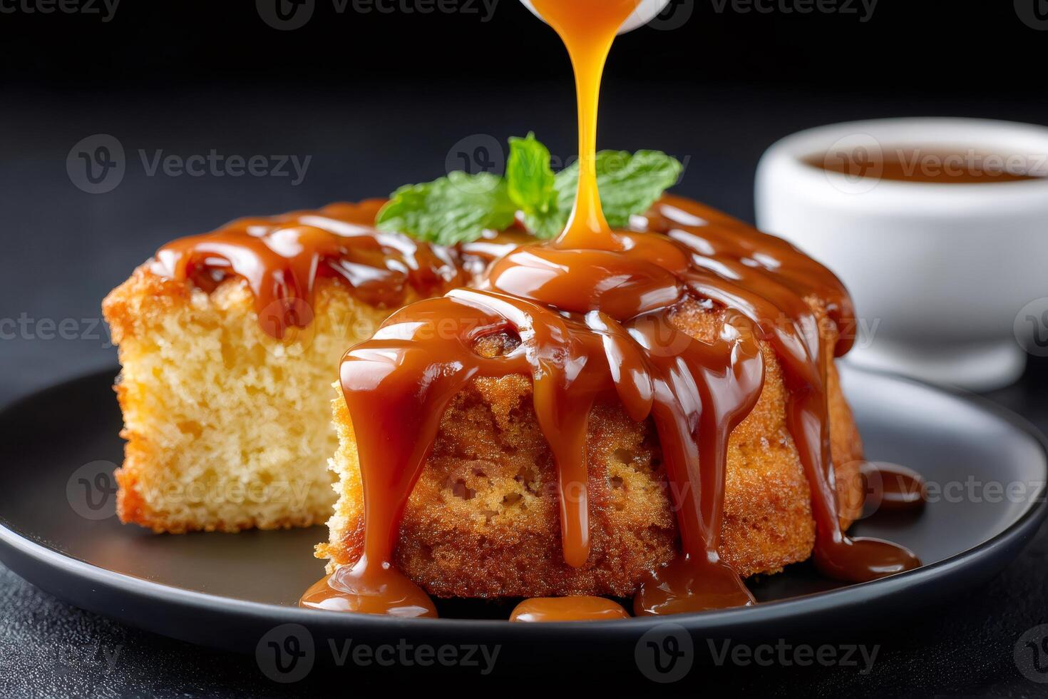 Delicious caramel sauce pouring on a cake with mint leaf on black plate photo
