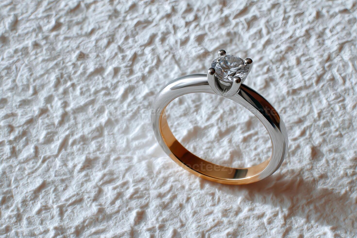 Elegant diamond solitaire engagement ring laying on white textured background photo