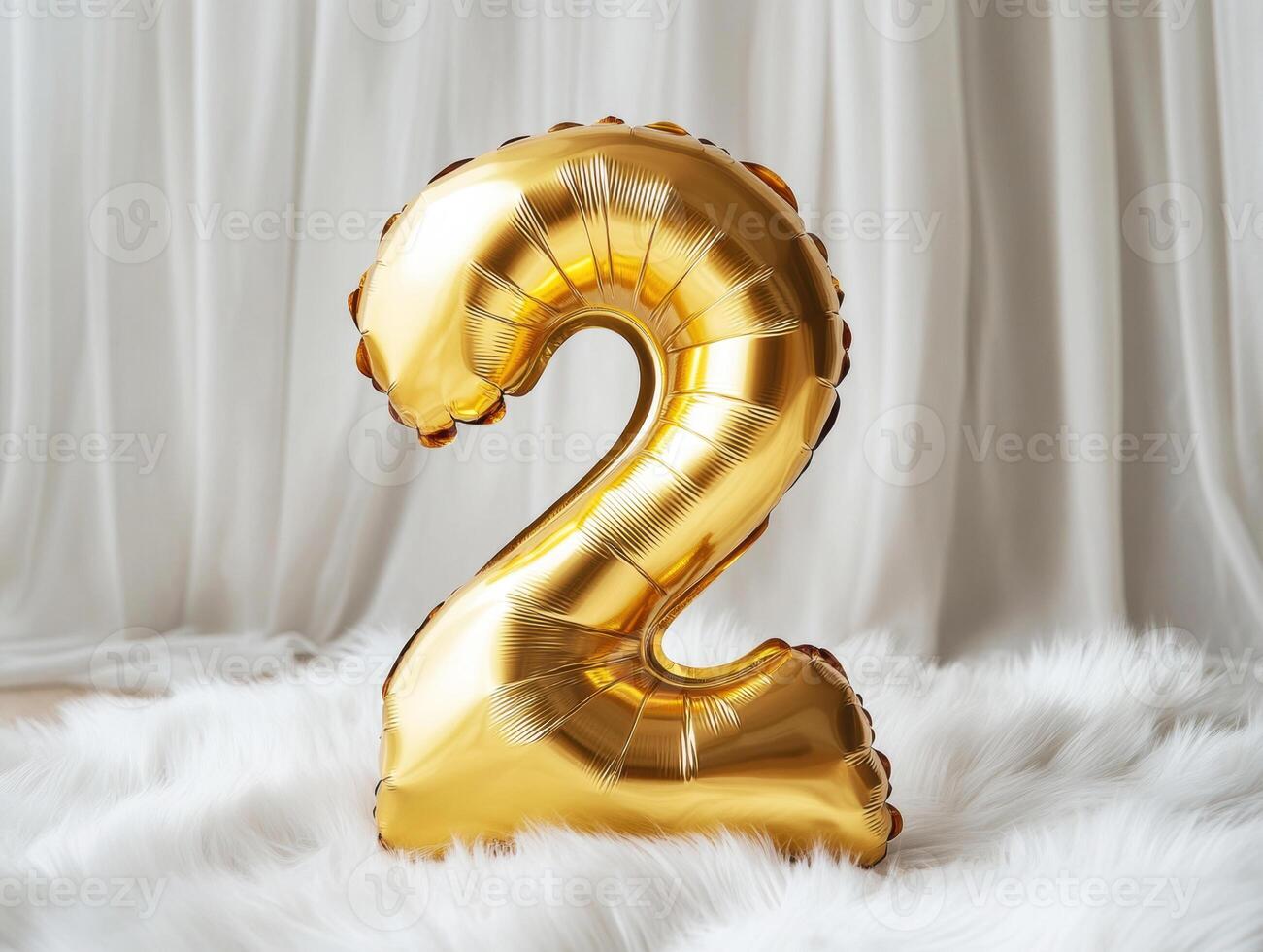 Golden number two balloon on soft white fabric background photo