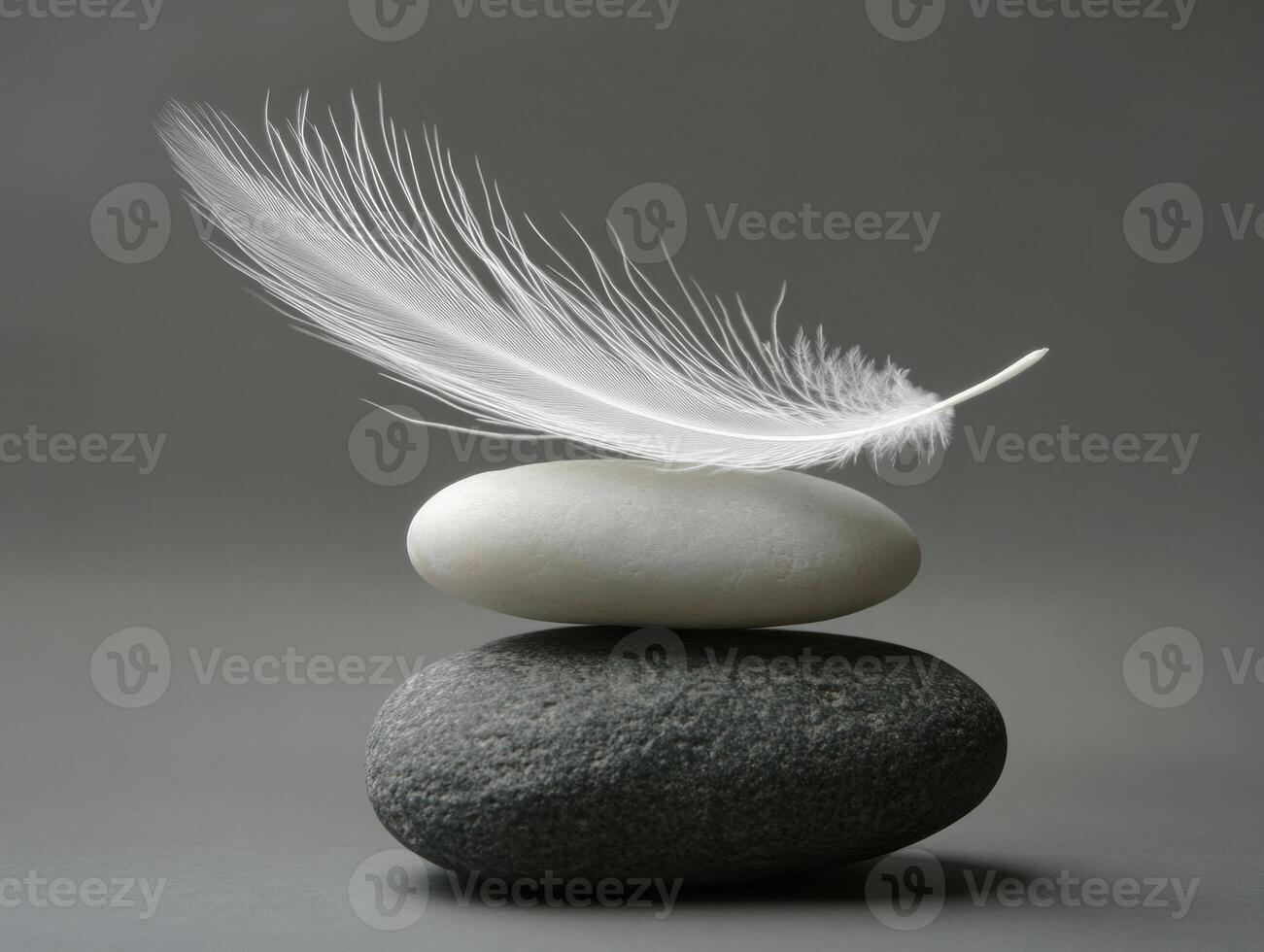 Feather resting delicately on stacked stones in serene arrangement photo